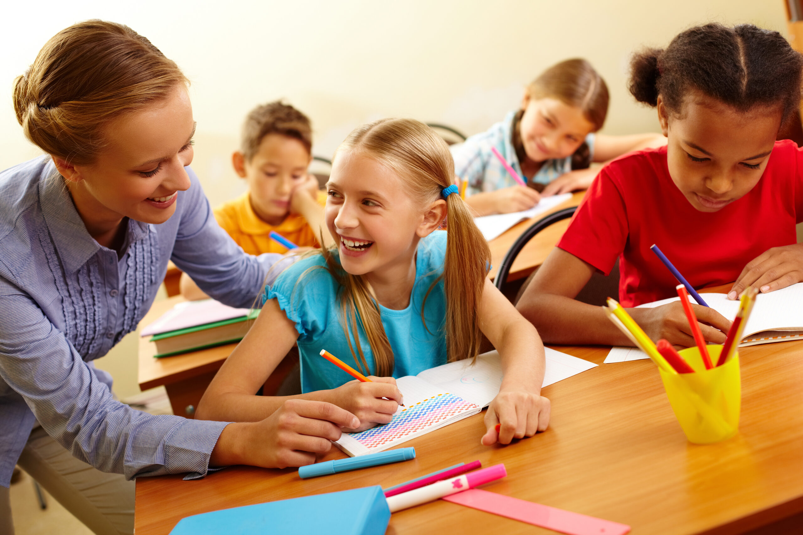 Portrait of smart girl and her teacher looking at each other at lesson in classroom